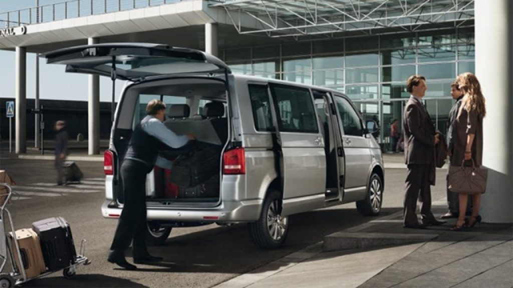 A minivan being loaded with luggage outside an airport terminal
