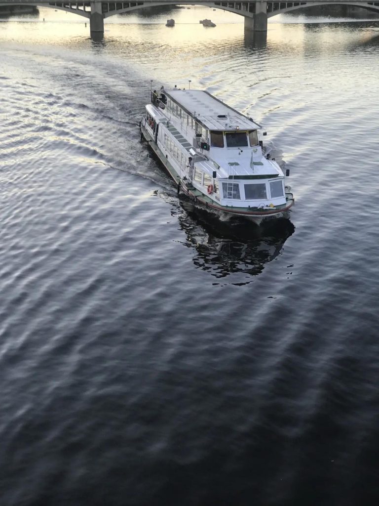 A sightseeing boat on the Vltava passing under a bridge in Prague