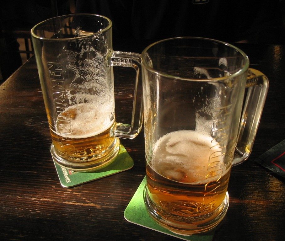 Two half-finished beer mugs with rings of foam on the glass