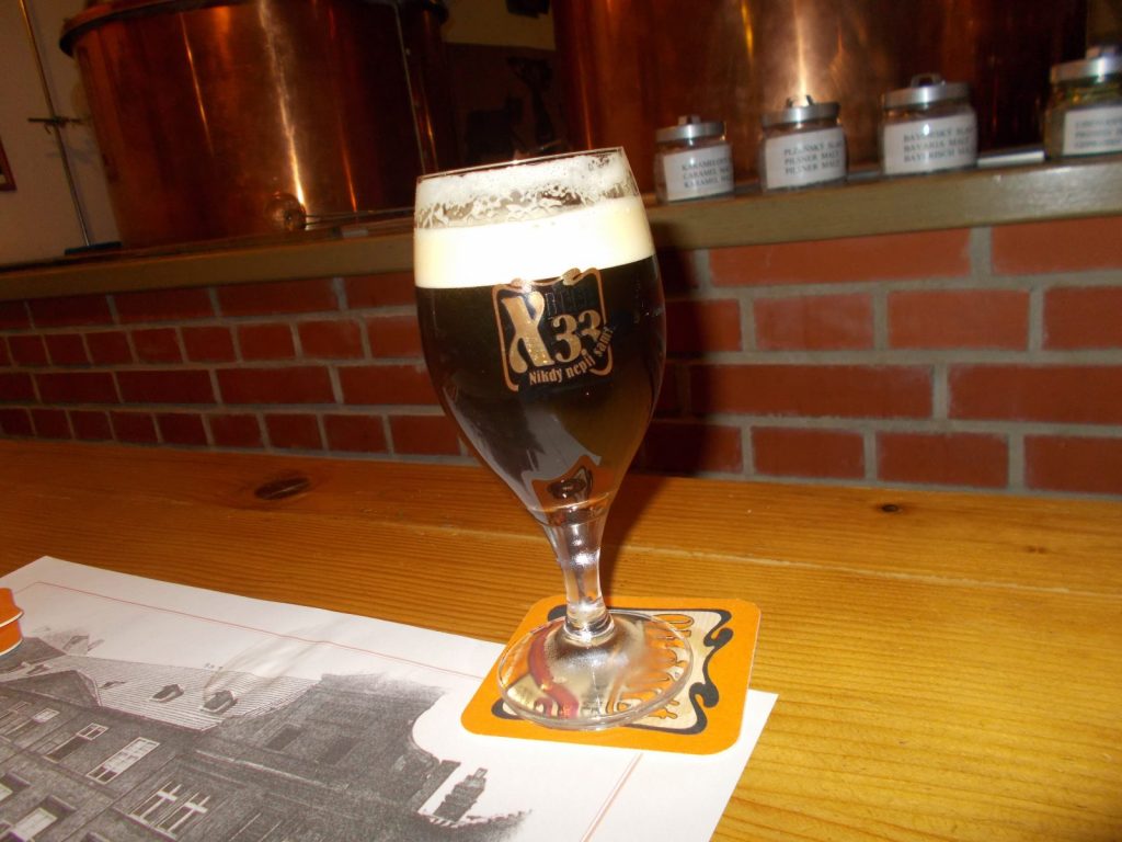 A glass of lager with a firm head of foam on a beer mat at a Prague bar